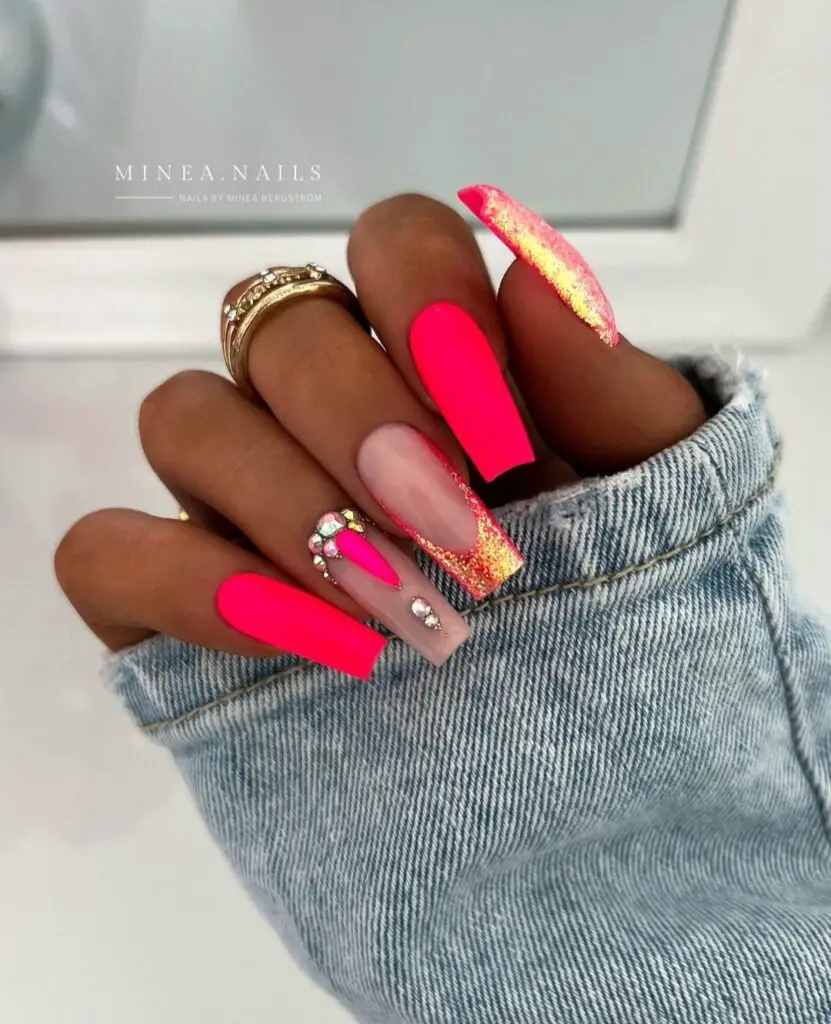 Neon pink nails decorated with stones and glitter