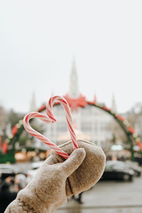 Free Christmas Candies Held in a Glove and City Architecture in Background Stock Photo